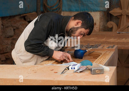 Artisan carving Armenian khachkar, Yerevan, Armenia, October 2012: A young Armenian artisan carves an Armenian cross stone at his workshop in Yerevan. Stock Photo