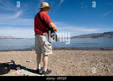Man plays guitar on beach at Lake Mead National Recreation Area Nevada, USA. Stock Photo