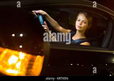 Driving a car at night - pretty, young woman driving her modern car at night in a city Stock Photo