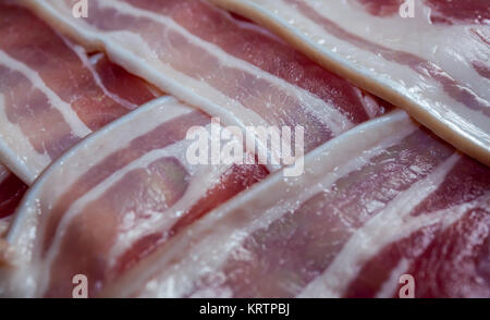 Streaky bacon rashers with rind on arranged in an overlapping pattern Stock Photo
