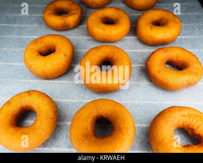 Closeup of freshly made dark brown doughnuts on baking paper Stock Photo