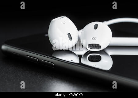 Close-up headphone stack on phone, modern phone's earbuds device accessories Stock Photo