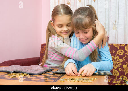 The older sister comforting crying younger sister, which collects a stack of coins Stock Photo