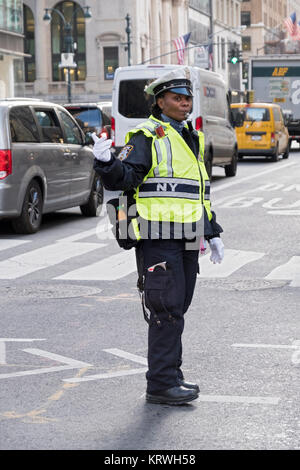 A policewoman directing traffic on Fifth Avenue and 43rd Street in Midtown Manhattan, New York City. Stock Photo
