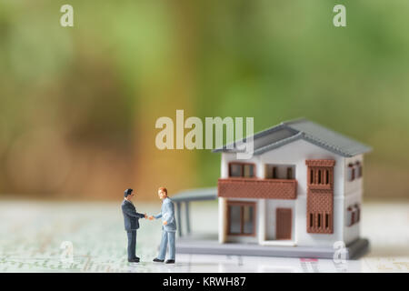 Miniature 2 people businessmen Shake hands with A model house model .as background  business concept and real estate concept with copy space. Stock Photo