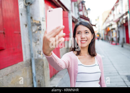 Woman taking selfie by mobile phone in Macau city Stock Photo