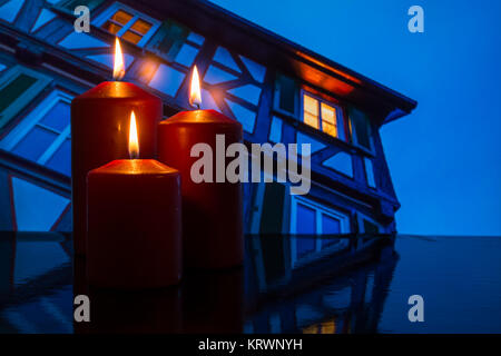 burning candles and home with windows and light Stock Photo