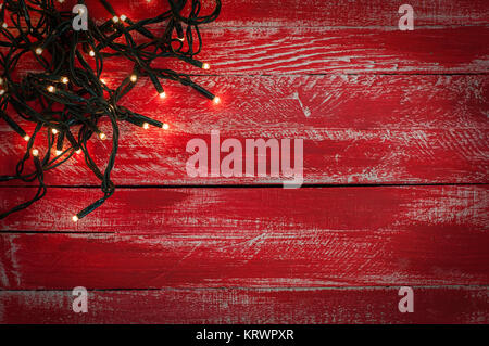 Christmas garland with small light bulbs on the red shabby wooden surface Stock Photo