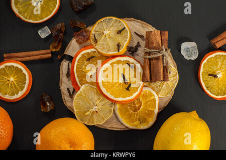 Fresh and dried oranges and lemons on a black surface Stock Photo
