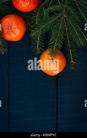 Mandarins with branch fir on a black wooden background Stock Photo