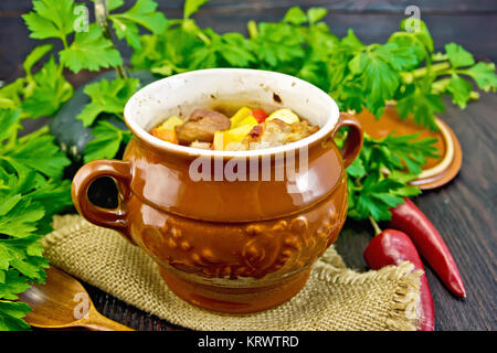 Roast meat and potatoes in pot on dark board Stock Photo