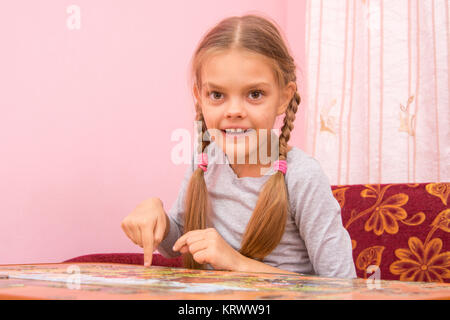 Girl collects a picture of the puzzle, and looked into the frame Stock Photo