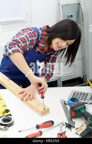 smiling woman assembling wooden planks using screwdriver Stock Photo