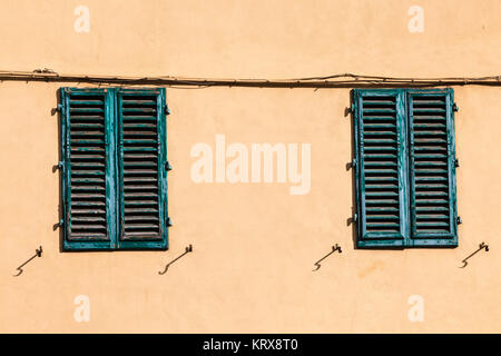 closed green windows on yellow wall of old house Stock Photo
