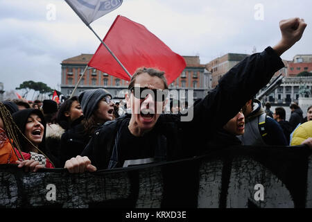 Protesters shout while holding a large red card that bears the ...