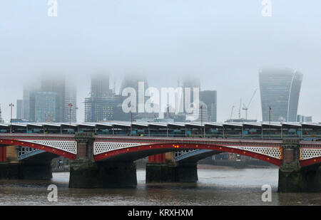 London, UK. 21st Dec, 2017. Blackfriars station over the river Thames in central London on a misty and foggy, rainy morning with the walkie talkie and the office buildings of the city of London with their tops in the low cloud base. Clouds and murky, rainy weather over the city of London and the river Thames. Credit: Steve Hawkins Photography/Alamy Live News Stock Photo