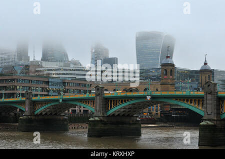 London, UK. 21st Dec, 2017. a misty or foggy morning over the river Thames with Southwark Bride and Cannon Street station in front of the iconic buildings of the city of London with their tops in the mist. The damp and rainy weather obscuring the tops of the tall office buildings in the fog and low cloud. Low cloud base hiding the tops of the buildings of the city. Credit: Steve Hawkins Photography/Alamy Live News Stock Photo