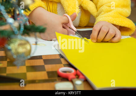 The child cuts out a star from construction paper, preparing a Christmas crafts, close-up Stock Photo