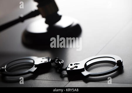 Criminal law concept. Cuffs and jugde gavel on stone background. Stock Photo