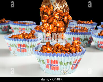 Puffed rice chocolate cup cakes being filled, on white table towards black Stock Photo