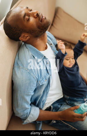 Sleeping and tired child with caring father holding his sleepy son on a