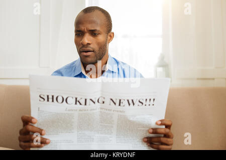 Baffled man reading shocking news Stock Photo