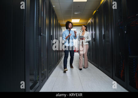 Young couple working at a data center. Black server room. Stock Photo