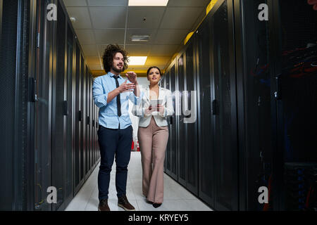 Young couple working at a data center. Black server room. Stock Photo