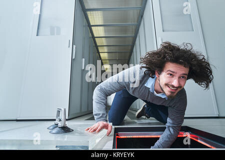 Young man fixing something in the floor hatch. Data center. Servers Stock Photo