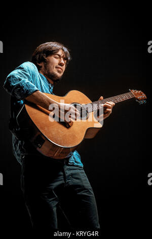 Cool guy standing with guitar on dark background Stock Photo