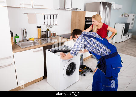 Male Worker Repairing Washer In Kitchen Room Stock Photo