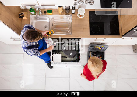 High Angle View Of Male Worker Repairing Washer In Kitchen Stock Photo