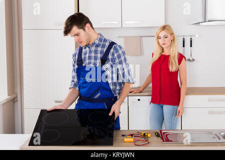 Male Repairman Installing Induction Cooker In Kitchen Stock Photo