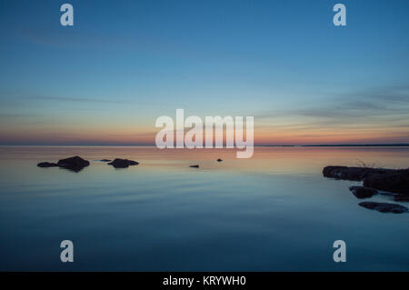 Calm lake huron sunset with rocks Stock Photo