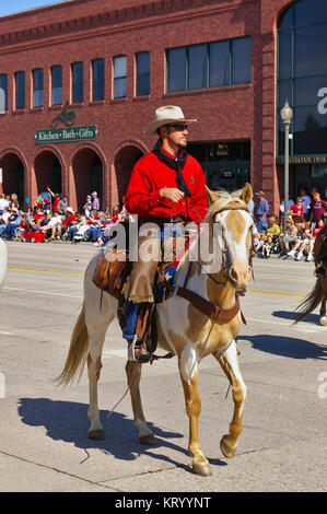 Cody, Wyoming, USA - Cowboy with bright red shirt riding on the Independence Day Parade Stock Photo