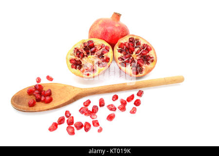 Pomegranate and two cut halves with seeds removed with spoon Stock Photo