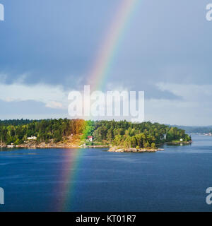 island with settlement and rainbow in blue sky Stock Photo