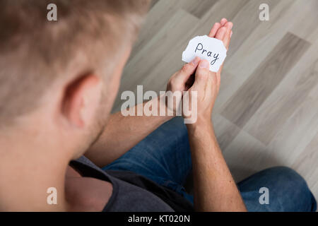 Piece Of Paper With Text Pray In Man's Hand Stock Photo