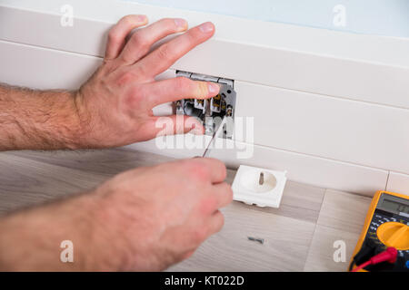Man's Hand Repairing Wall Fixture Stock Photo