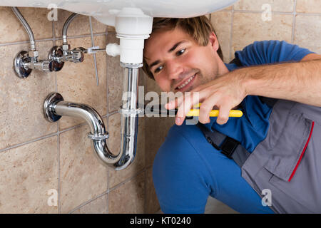 Male Plumber Repairing Sink In Bathroom Stock Photo