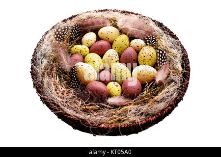 Decorative Easter eggs in basket with hay and Guinea fowl feathers Stock Photo