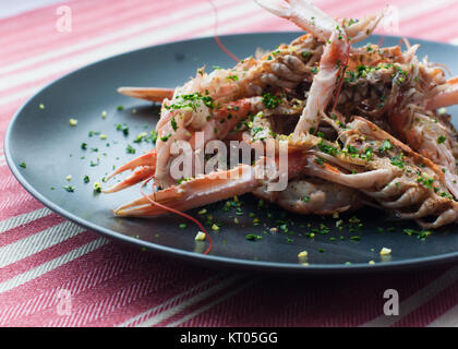 fresh cooked lobster with herbs on black plate with red and white stripe table cloth Stock Photo