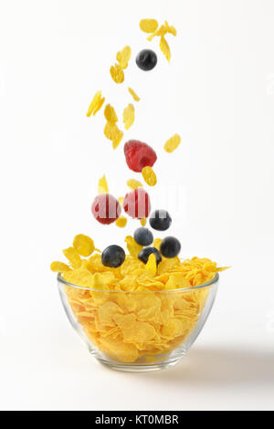 berry fruit and corn flakes falling into bowl Stock Photo