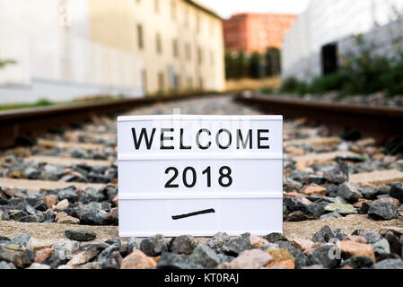 a lightbox with the text welcome 2018 placed on a railroad track, metaphor of the beginning of a new year as a journey Stock Photo