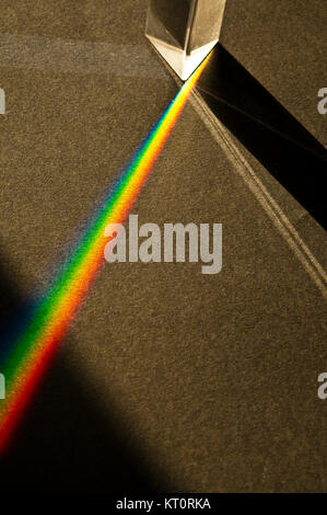 glass prism creating rainbow light effect on a black surface Stock Photo