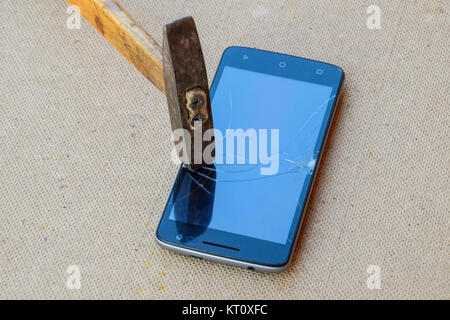 Hammer and smartphone. The screen of the smartphone, a broken ha Stock Photo