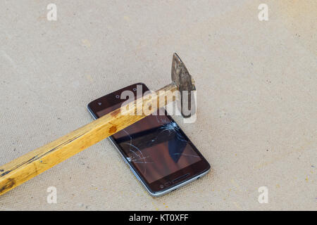 Hammer and smartphone. The screen of the smartphone, a broken ha Stock Photo