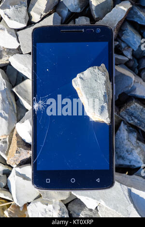 Frustrated phone on the rocks. Glass shattered on rocks on a sma Stock Photo