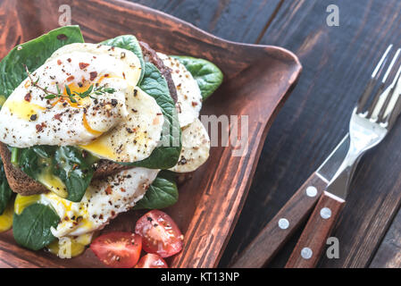 Sandwich with poached eggs, mozzarella, spinach and cherry tomatoes Stock Photo