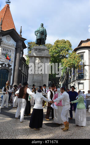 Group of folk musicians and folk dancers performing on the Avenida Arriaga with the iconic Bank of Portugal in the background, Funchal, Madeira. Stock Photo